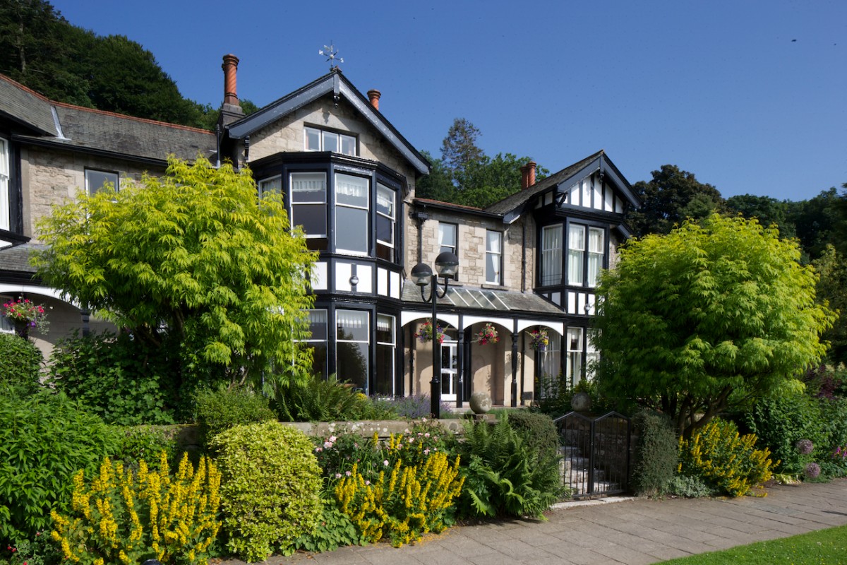 The stone and timber frontage of Castle Green Hotel surrounded by gardens