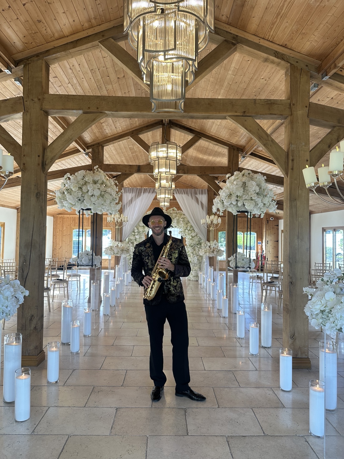 Spencer with his saxophone in Colshaw Hall’s ceremony room, surrounded by white flowers and candles