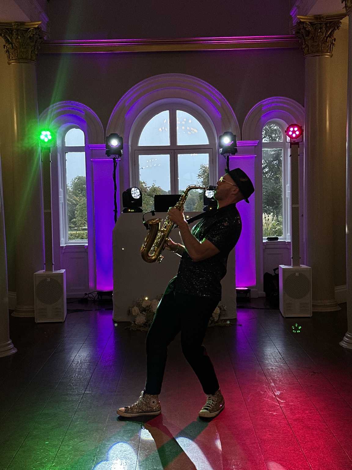 Spencer playing saxophone with colourful DJ lighting behind him
