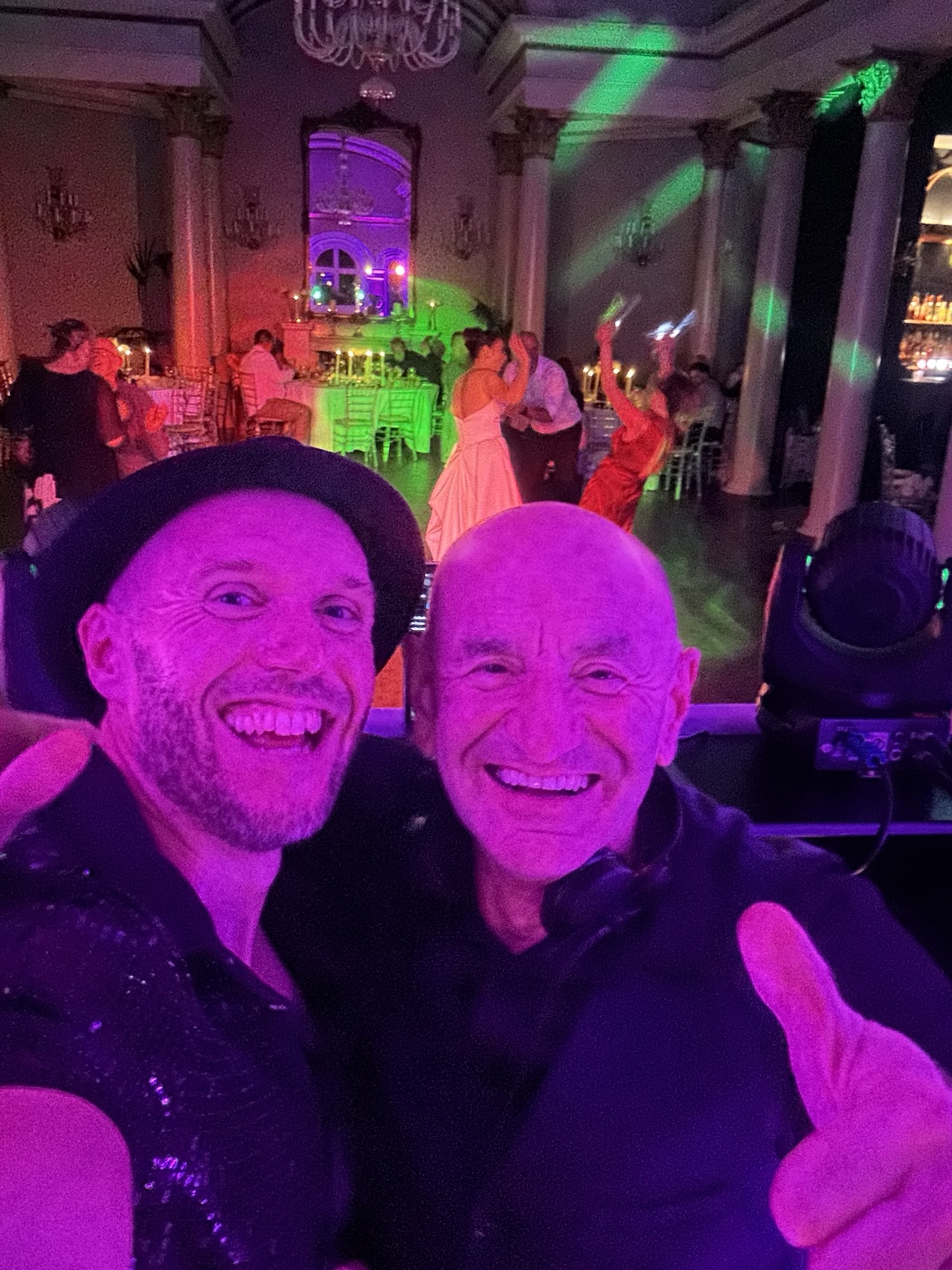 Spencer and DJ Ian Conway with the wedding party and colourful lights behind them