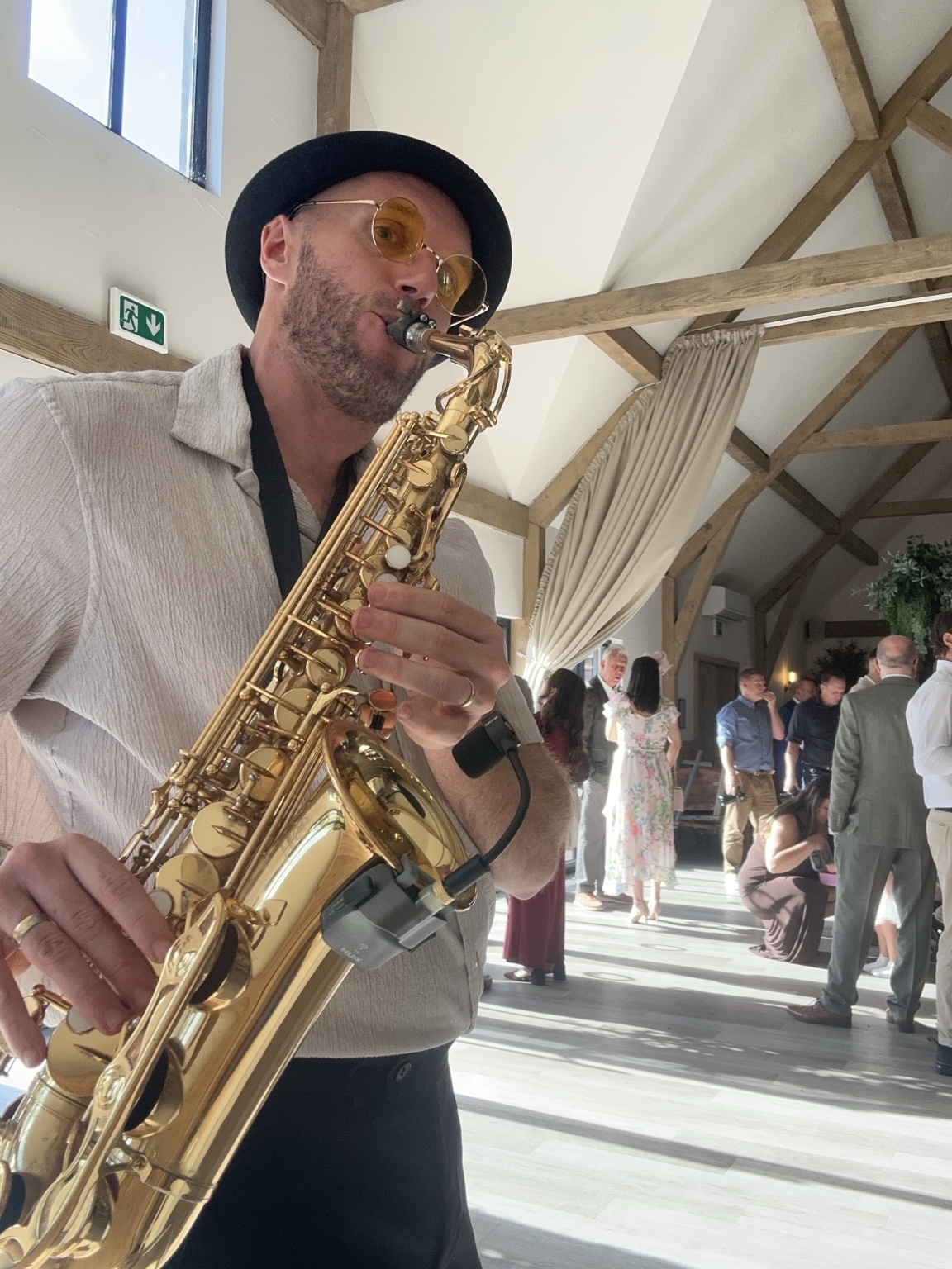 Spencer playing sax among guests at The River Barn drinks reception