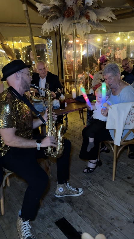 Spencer playing sax for Claire and Ryan’s little boy sitting on his grandma’s lap