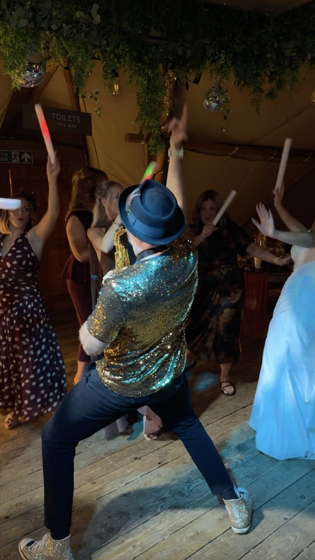 Spencer playing sax surrounded by guests at Claire and Ryan’s evening party