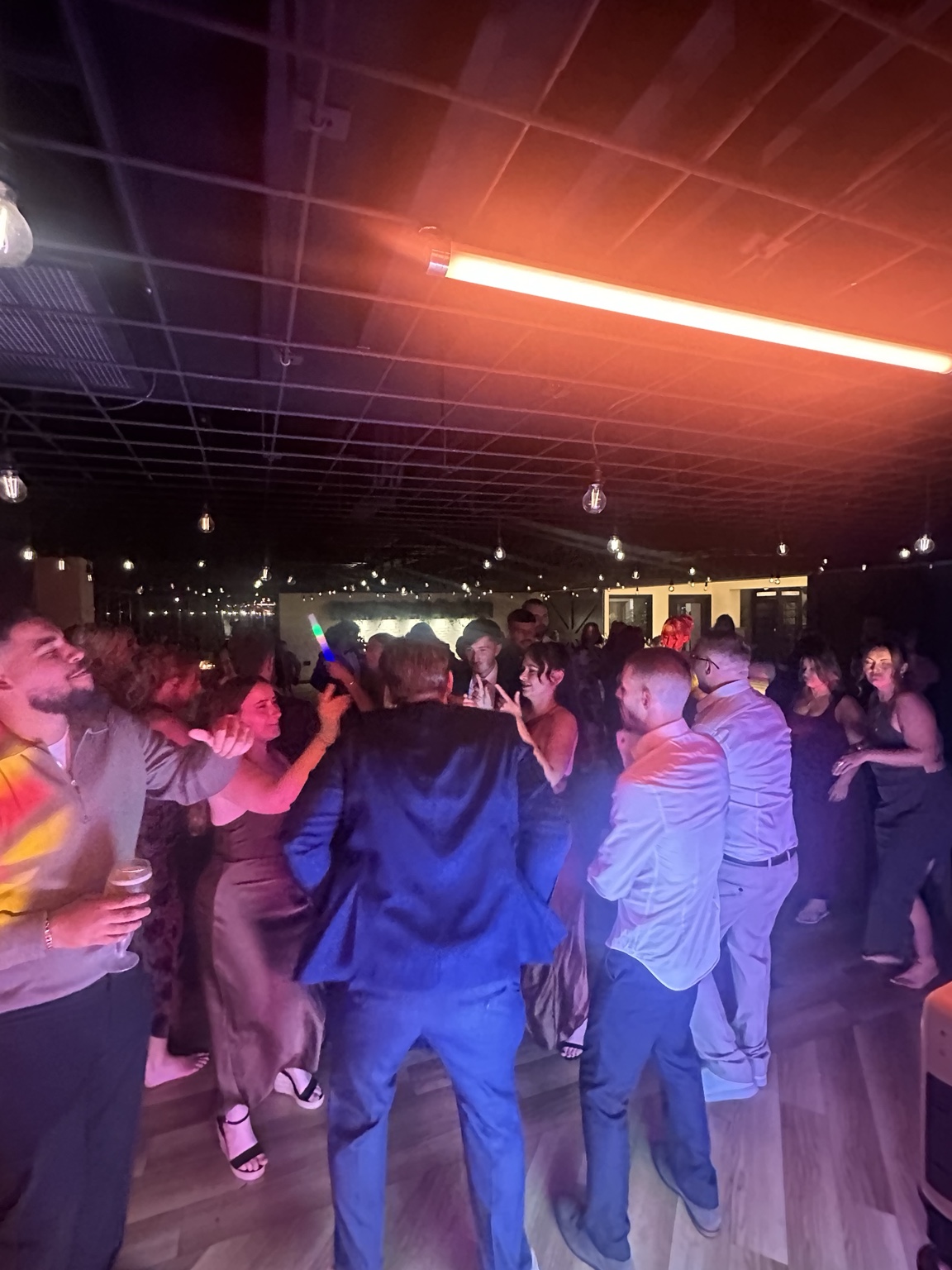 Wedding guests dancing beneath the lights at Whistle Barns